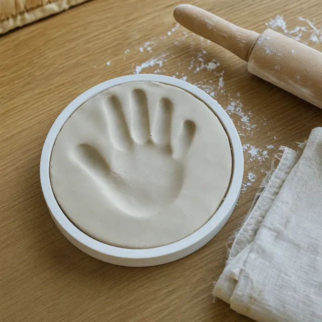 Baby hand impression in air-dry clay on a wooden table, sculptural keepsake